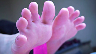 Young girl with beautiful feet plays with a toy