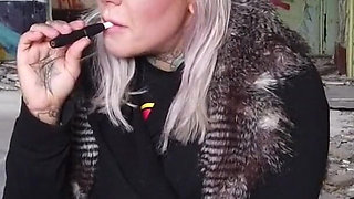 Blonde lady smokes an electronic cigarette on stair