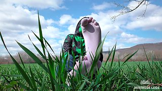 Feet in Cute White Socks with Jeans on the Grass Field